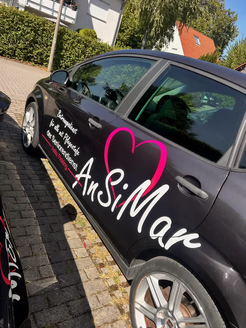 Dunkles Auto mit der Aufschrift AnSiMar und einem großen pinken Herz auf den Türen